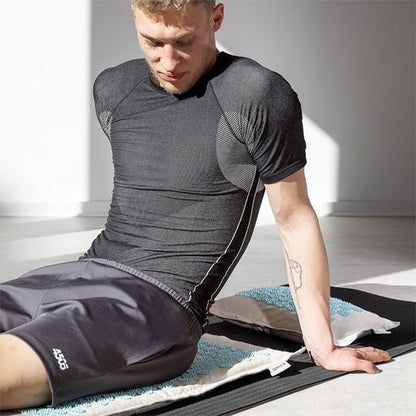homme assis sur tapis d'acupression lin coco bleu